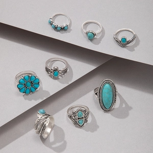 Macro shot of 8pcs vintage bohemian silver rings set with turquoise on geometric background