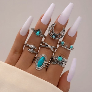 Close-up of bohemian silver rings with turquoise, feathers, and snakes on fingers