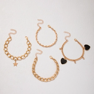 Detailed view of four-piece gold bracelet set with star and black heart charms