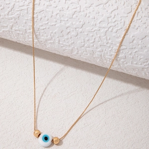 Minimalist gold evil eye pendant necklace with blue bead on white stone backdrop