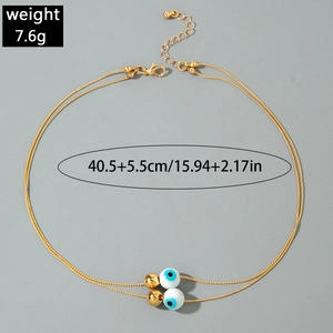 Close-up of gold double-layer necklace with blue evil eye beads and weight specifications