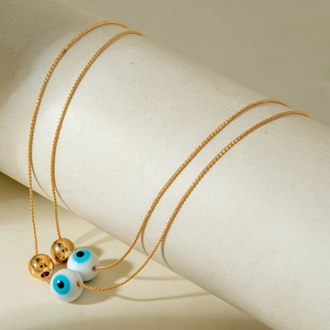 Detail of golden chain necklaces with blue evil eye charms and polished gold beads