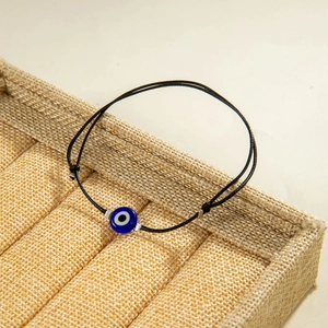 Detail of handcrafted black cord bracelet with a blue Evil Eye bead and silver accents