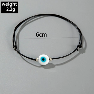 Detail of adjustable handmade black cord bracelet featuring a blue evil eye bead and silver spacers