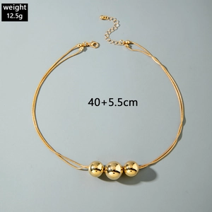 Detailed shot of double snake chain gold necklace with three polished round beads
