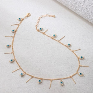 Gold evil eye necklace with vertical bar pendants on white textured stone surface