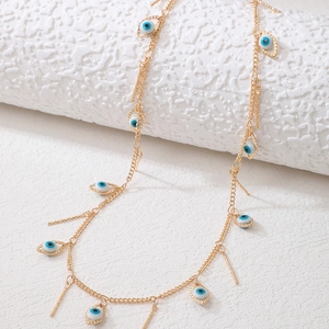 Golden Evil Eye necklace with vertical bar pendants on a textured white surface