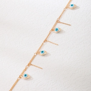 Gold evil eye necklace with vertical bar pendants on textured white background