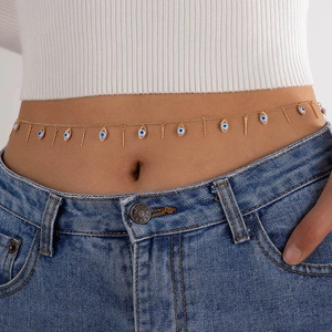 Detail of gold belly chain with evil eye charms and vertical bars on a waist