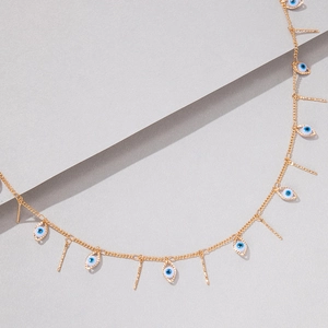 Close-up of golden evil eye necklace with vertical bars on a minimalist background