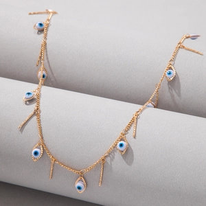 Detail view of gold chain with blue evil eye beads and vertical bar pendants