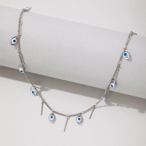 Detailed view of silver evil eye and vertical bar charms on a delicate chain necklace