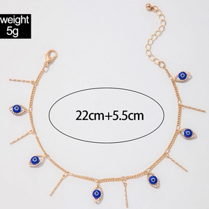Detail of gold evil eye and vertical bar pendant necklace on a clean grey backdrop