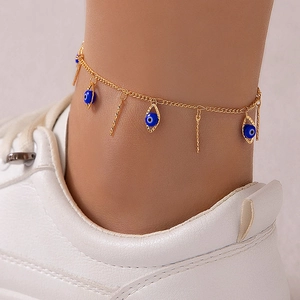 Detail of golden evil eye ankle bracelet with blue pendants and gold vertical bar charms