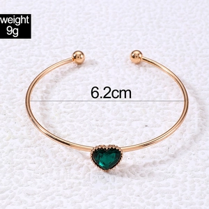 Detailed view of open cuff bracelet with green heart gem and 6.2cm inner diameter