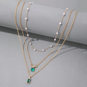 Détail du collier triple rang doré avec perles et pierres précieuses vert émeraude