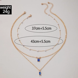 Détail du collier multicouche doré avec pendentifs émeraude et perles de 24g de poids