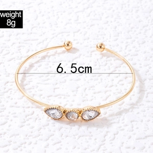 Macro shot of gold-plated bangle showing 8g weight and 6.5cm diameter measurement