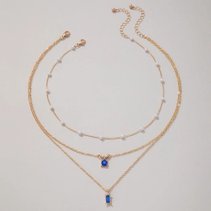 Détail du collier doré multicouche avec pierres bleues et petites perles blanches
