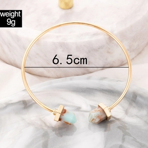 Detail view of gold open cuff bracelet with marble texture resin hexagon accents