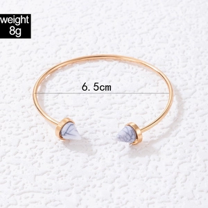 Detailed view of golden open bangle with marble triangle ends and 6.5cm diameter measurement