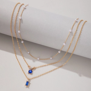 Détail d'un collier triple couche en or avec pierres précieuses vertes et perles blanches