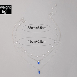 Détail du collier triple rang avec pendentifs bleu émeraude et perles blanches