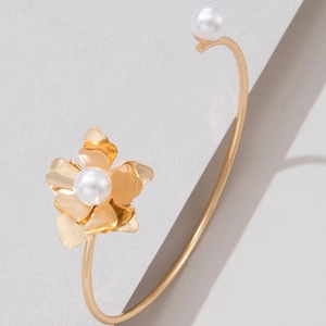 Macro shot of gold floral open bangle featuring detailed layered petals and white pearls