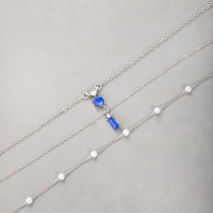 Détail du collier argenté multicouche avec pierre bleue émeraude et perles blanches