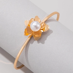 Macro shot of gold floral open bangle featuring a large white pearl center and 3D petals