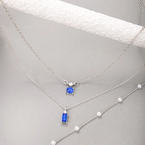 Détail du collier argenté à trois rangs avec pierres bleues et perles blanches