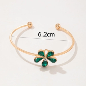 Macro detail of gold flower cuff bracelet with green gems and 6.2cm inner diameter