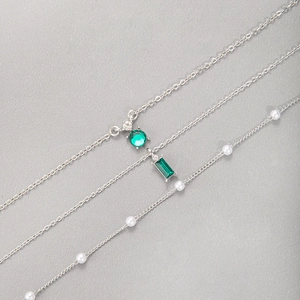 Détail de colliers en argent avec pendentifs émeraude verte et perles blanches