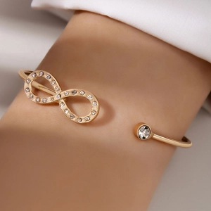 Detailed close-up of golden infinity charm bracelet with sparkling crystal inlay