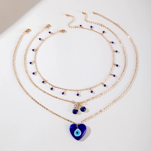 Détail du collier doré multi-rangs avec pendentifs cœur œil bleu et petites cerises