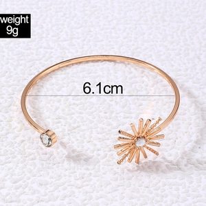 Detailed view of golden open bangle with flower petal and pearl accents showing 6.1cm diameter