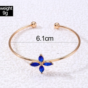 Detailed view of gold open bangle with blue petal crystals showing 6.1cm inner diameter