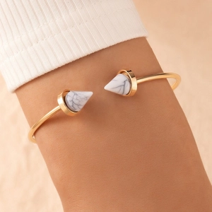 Elegant gold open bangle featuring white marble texture cone tips on a wrist