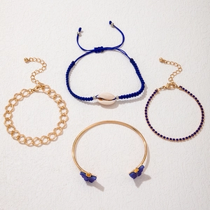Détail d'un ensemble de quatre bracelets dorés avec papillons bleus et pendentif coquillage