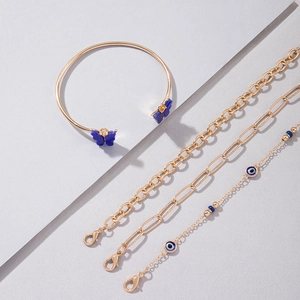 Détail d'un ensemble de bijoux dorés avec breloque papillon bleu et perle de l'œil bleu