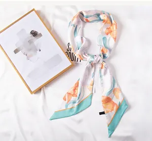 Detalle de pañuelo largo con estampado floral naranja, bordes azules y extremos en punta