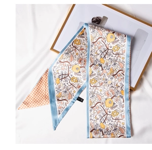 Close-up of floral twilly silk scarf with yellow flowers and orange houndstooth pattern