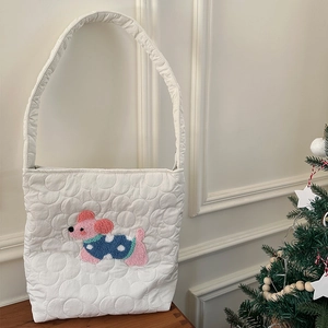 Vue détaillée du sac en toile matelassé blanc avec broderie de chiot rose sur table en bois