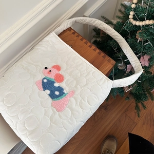 Détail du sac matelassé blanc avec surpiqûres florales et broderie de caniche mignonne