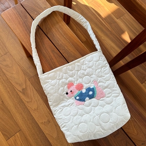 Détail d'un sac bandoulière blanc matelassé avec broderie de chien mignon et texture douce