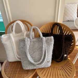 Detailed close-up of fuzzy plush tote bags in white grey and brown on wooden chairs