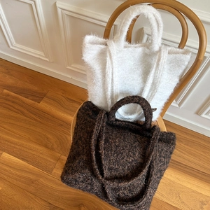 Detail of plush knitted tote bags in white and dark brown with round handles and straps