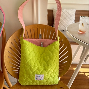 Detail of light green quilted heart pattern bag with pink contrast lining and logo tag