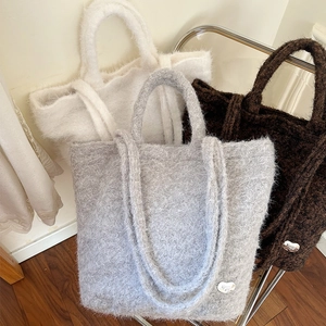 Close-up of fluffy faux fur tote bags in grey and brown colors with metal heart logo