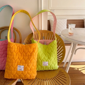 Detail of heart quilted texture on colorful crossbody bags in orange, green and pink